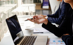 Peoples hands pointing at a laptop